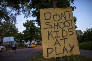 A man walks down a street past a handmade sign posted in the Englewood neighborhood in Chicago, Illinois, United States, July 29, 2015. Residents put the signs up in the area which has a high level of gun violence in hopes of reducing crime. REUTERS/Jim Young - RTX1MCAH